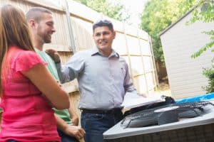 Air conditioner repairman explaining A/C damage to homeowners