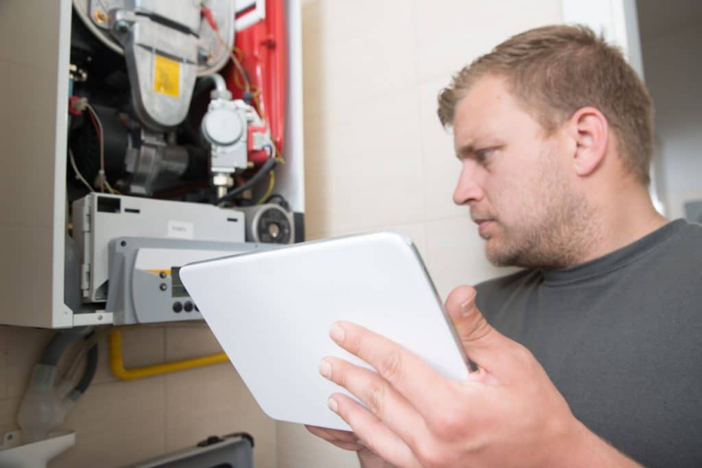 Technician repairing Gas Furnace using digital tablet