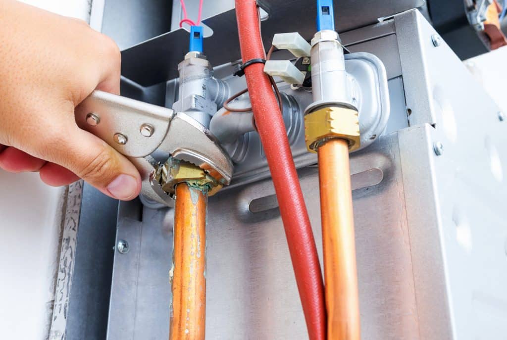 Plumber repairing a gas boiler of a heating home system in the boiler room. Close-up, selective focus.