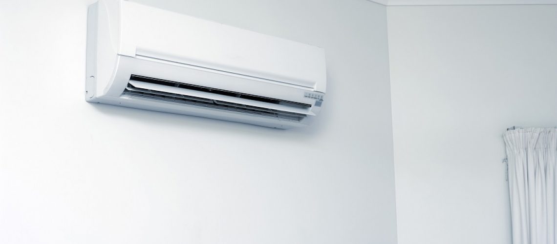 Close up Modern Domestic Air Conditioning Appliance Hanging on White Wall Inside a Room.
